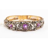 A Victorian style bangle comprising three emerald  cut amethysts set within open scroll work details