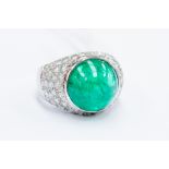 An emerald and diamond set dress ring, boule head set with a large cabachon  cut emerald (possibly