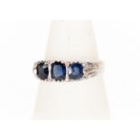 A three stone sapphire and diamond ring, comprising three oval mixed cut sapphires set in 14ct gold,