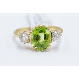 A peridot and diamond ring, oval claw set peridot to the centre weighing approx 2.2 carat, set