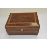 A Regency flame mahogany work casket of sarcophagus form, boxwood strung, brass ball feet