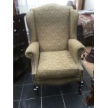 Large wing back arm chair in gold and green.