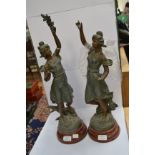 A pair of French spelter sculptures of ladies with floral bouquets, named Chrysanthemum and Anemone