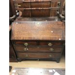 A George III oak and mahogany cross-banded bureau, the fall front enclosing a fitted interior,
