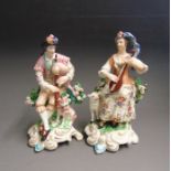A pair of Derby figures of  seated musicians, he with a dog and she with a sheep, incised No.301,