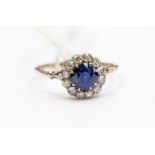 A sapphire and diamond cluster ring, the round cut sapphire approx 0.70ct with a diamond surround of