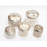 Five glass dressing table jars all with silver lids, Chester 1918, Birmingham 1923 and 1903,