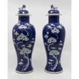 A pair of 19th Chinese blue and white vases, with covers, blue ground, prunus pattern