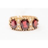 A garnet and white stone dress ring, set with three oval garnets, with white stone accents, 9ct gold