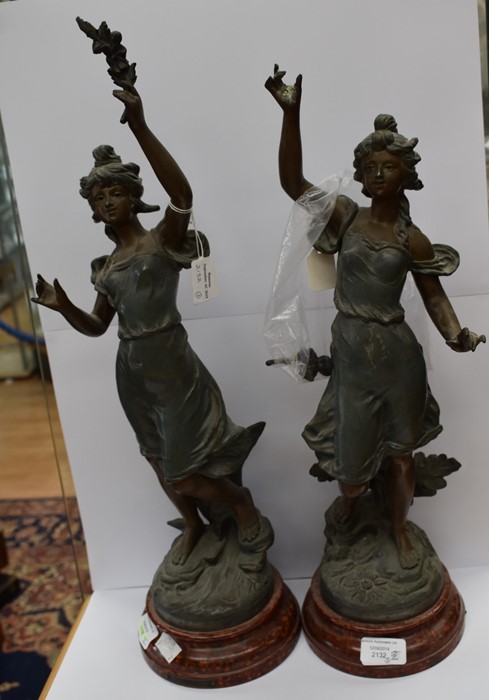 A pair of French spelter sculptures of ladies with floral bouquets, named Chrysanthemum and Anemone