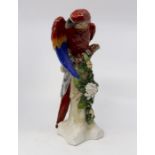 Dresden late 20th Century red and blue parrot on tree with floral detail, blue stamp to base, 30 cms