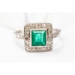 An emerald and diamond ring, the central square cut emerald weighing approx 0.85ct, set withing a