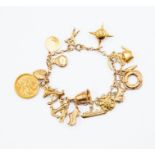 A 9ct gold charm bracelet, suspending numerous charms including George V half sovereign, sputnik,