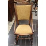 A late 20th Century oak rocking chair with gold upholstered seat and back with decorative studs.