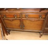 Oak sideboard with carving. Three drawers over two cupboards, raised on turned legs.
