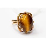 A tigers eye dress ring, fancy mount claw set in unmarked yellow metal probably 9ct gold, oval