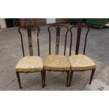 Three Edwardian mahogany side chairs upholstered in gold fabric.