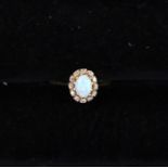 An opal and diamond cluster ring, the oval opal measuring approx 4mm x 6mm, with a diamond set