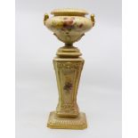 A Royal Worcester blush vase in the form of an urn on pedestal stand, floral decoration heightened