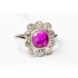 A ruby and diamond cluster ring, the cushion cut Burmese Ruby,  rub-over set with millegrain detail,