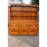 A late 20th Century light oak dresser and plate rack, having three drawers over three cupboards.