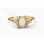 An opal and diamond ring, claw set diamonds set either side of an oval opal, unmarked yellow