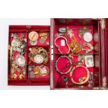 A burgundy leather jewellery case with internal tray and compartments housing a collection of