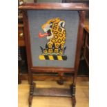 A wooden fire screen with wool work panel depicting a leopard.