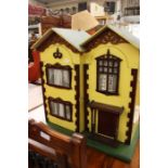 A vintage wooden dolls house with hinged front, four rooms containing assorted furniture and dolls