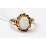 An opal dress ring, oval opal with a 9ct gold rope surround, opal with pink and green play of