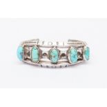 A Native American turquoise and white metal torque bangle, set with five oval cabochon turquoise,