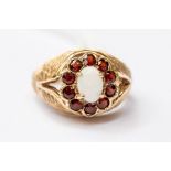 An opal and garnet dress ring, the oval opal with a stone set border,  9ct gold textured shank, size