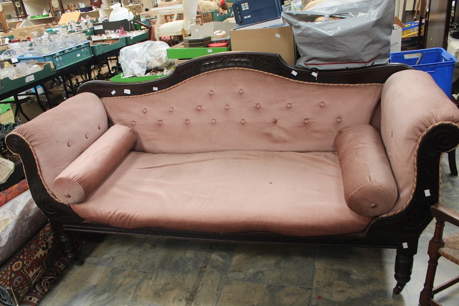 A mid Victorian Carved Mahogany Settee, c.1870, pink upholstery raised on turned supports on