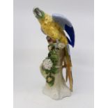 Dresden late 20th Century blue and yellow parrot on tree, floral detail, blue backstamp, 32 cms high