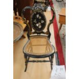 A Victorian black lacquered Bergere bedroom chair, inlaid with mother of pearl