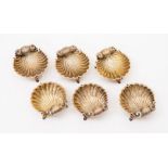 A set of six silver gilt scallop shell shaped salts, each standing on three stylised dolphin feet,