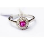 A ruby and diamond cluster ring, the central ruby weighing approx 0.50ct, with a diamond set