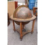 A decorative cocktail cabinet in the shape of a globe in a pedestal base on castors.