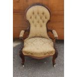 A Victorian mahogany button back armchair with porcelain castors upholstered in gold .