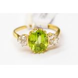 A peridot and diamond ring, oval claw set peridot to the centre weighing approx 2.2 carat, set