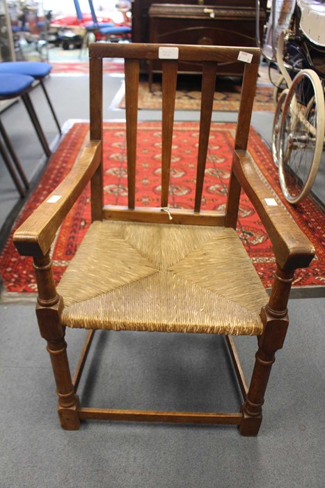 An Arts and Crafts Cotswold school oak child's armchair, with a vertical slatted back, rush seat,