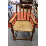 An Arts and Crafts Cotswold school oak child's armchair, with a vertical slatted back, rush seat,