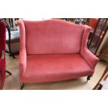 Pink upholstered two seater sofa.