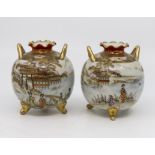 A pair of early 20th Century Noritake porcelain vases, raised on three feet with lug handles