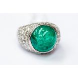 An emerald and diamond set dress ring, boule head set with a large cabachon  cut emerald (possibly