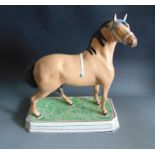 A rare large pottery pearlware model of a horse, standing on an oblong green base with maroon and