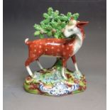 A Staffordshire pottery model of a doe standing before bocage, circa 1825, 18.5cm high, 14.5cm