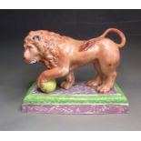 A Staffordshire pottery model  of a lion standing on an oblong base with pink lustre decoration,