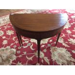 A Sheraton mahogany demi-lune card table, circa 1800, strung decoration, fold over top above a