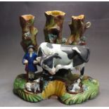 A Staffordshire pottery tree trunk group of a farmer his dogs and a cow, the word COW is written